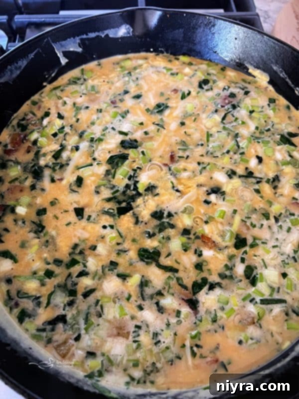 Bowl of whisked egg mixture with herbs and cheese