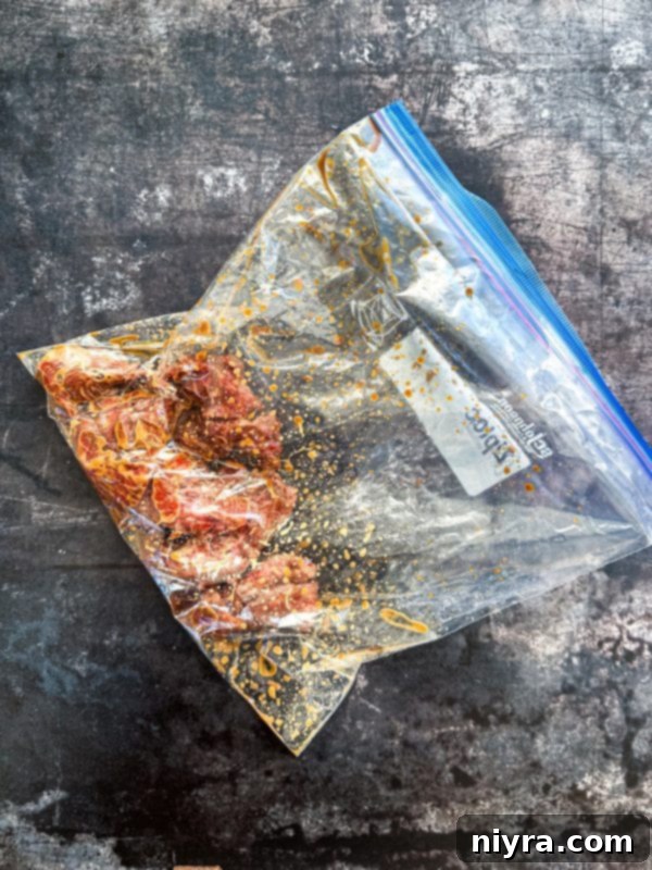 Beef strips coated in cornstarch, soy sauce, and sesame oil in a zip-lock bag.