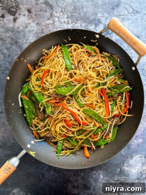 Cooked beef, vegetables, and noodles combined in a wok.