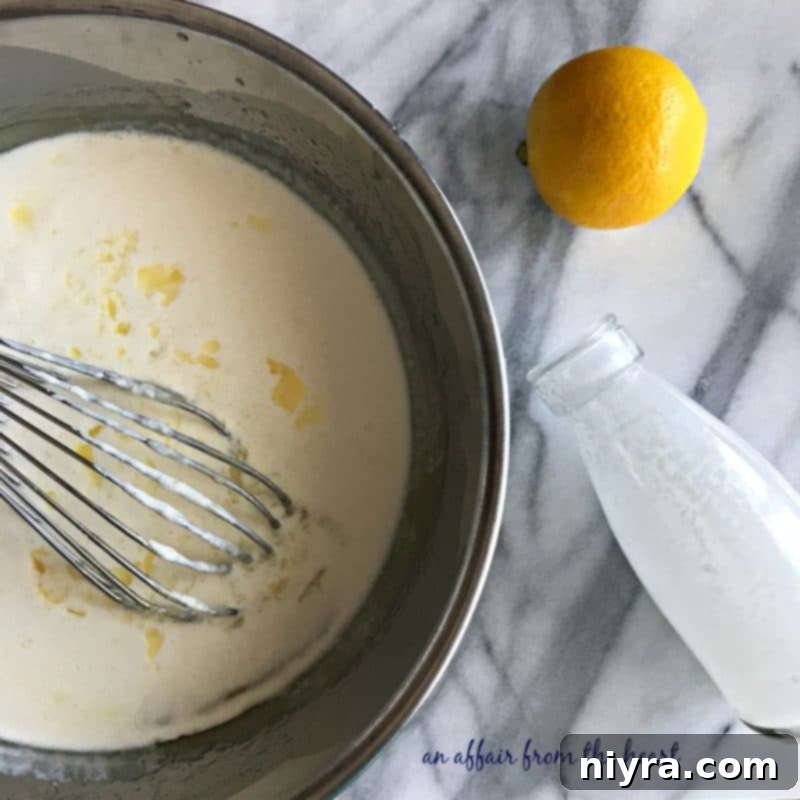 Lemon curd mixture in a bowl, after cooking, with heavy cream being added.