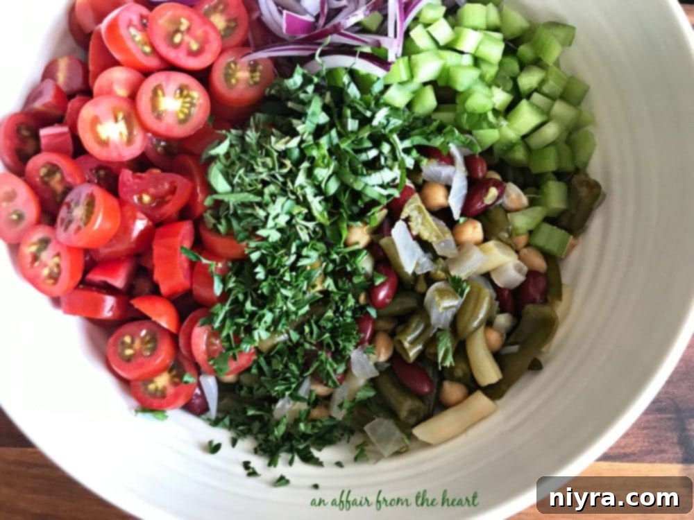All the Italian Bean Salad ingredients are tossed together in a large mixing bowl.