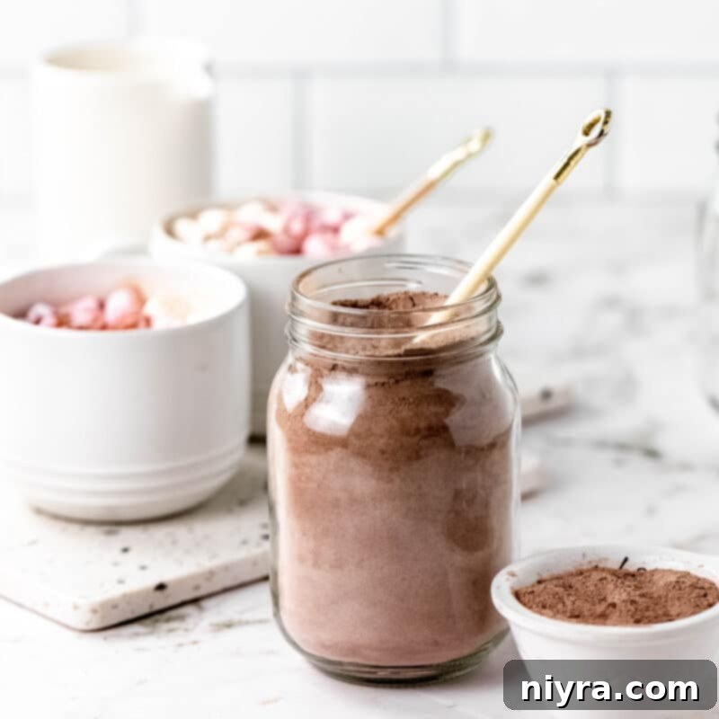 Cozy DIY Hot Chocolate Blend 11 Homemade hot cocoa mix in a jar with a scoop, marshmallows, and a mug on a festive background.