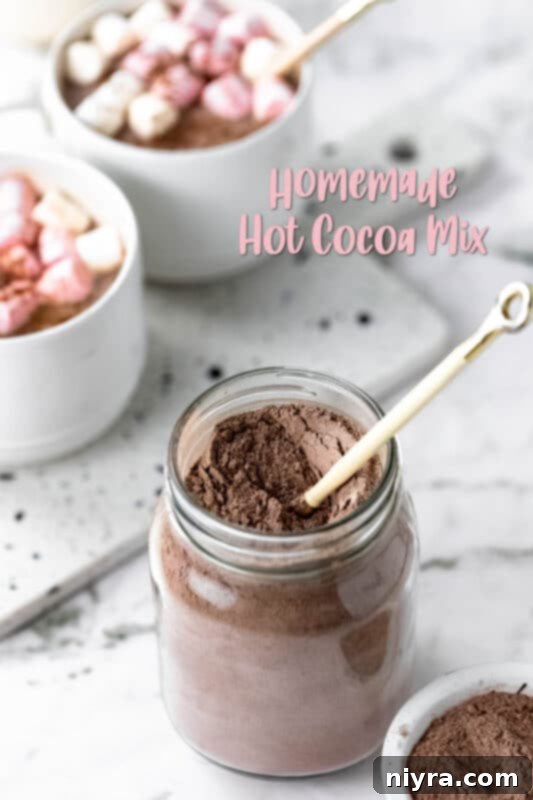 Cozy DIY Hot Chocolate Blend 15 A mason jar of hot cocoa mix with a wooden scoop and marshmallows next to a white mug.