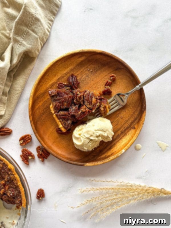 Pecan pie slice with a fork on a dark plate