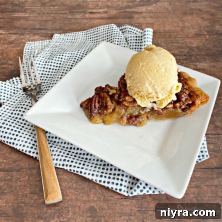 Pecan pie with a scoop of pumpkin ice cream on a white plate