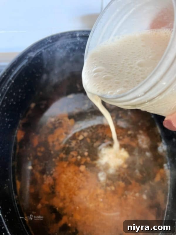 Step 5: Pouring the milk and flour mixture (slurry) into the bubbling pan drippings on the stovetop.