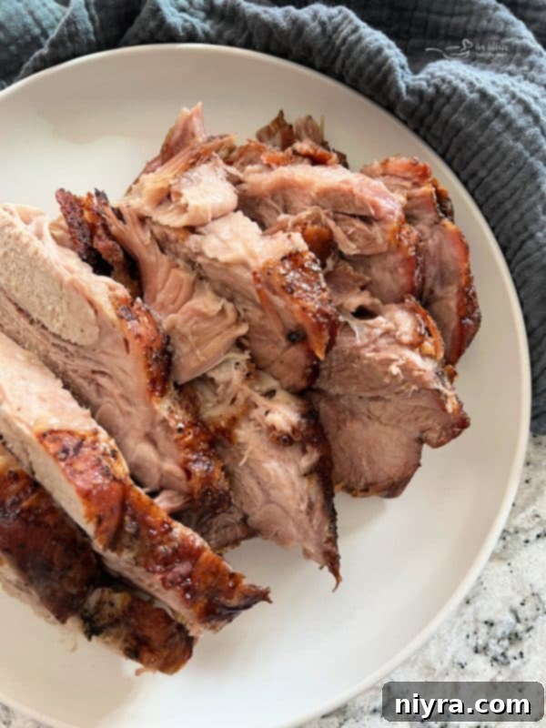 A platter of cooked, sliced pork roast with fresh herbs, ready to be served.