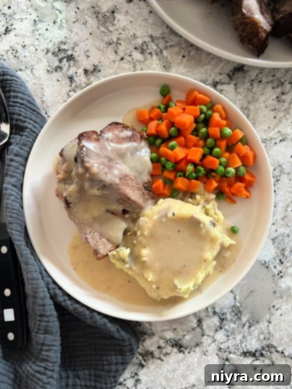 A close-up of the delicious pork roast with gravy, garnished with fresh herbs, ready for serving.
