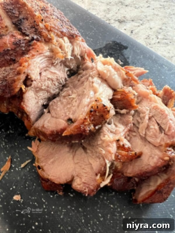 Close-up of slices of perfectly roasted pork with a generous amount of homemade gravy poured over them.