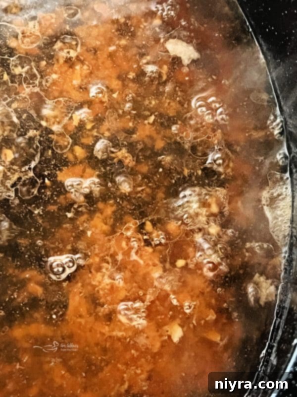 Step 4: Placing the roasting pan with pork drippings on the stove and adding water to bring to a boil.