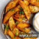 Roasted parmesan garlic potato wedges on a serving plate.