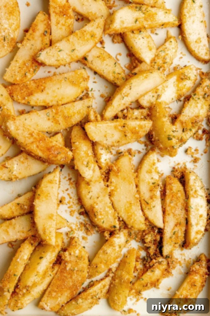Coating potato wedges with olive oil, parmesan, and seasoning
