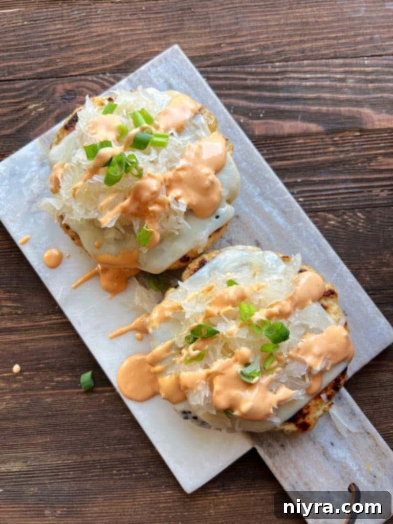 Assembling the Turkey Reuben Burger with a patty, melted cheese, and a generous heap of Frank's Kraut.