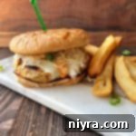 A Turkey Reuben burger and french fires on a white marble slab.