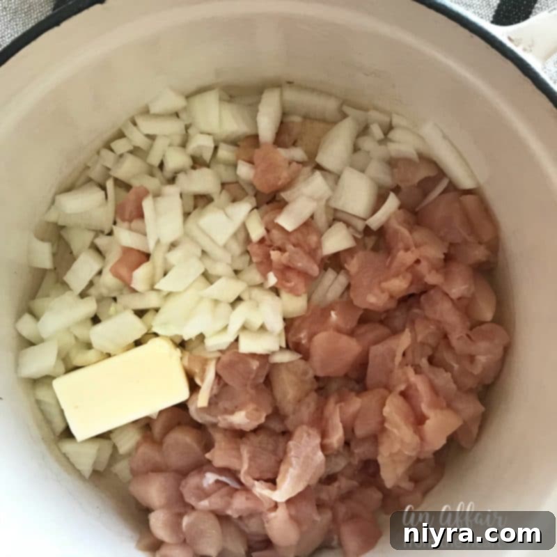 Cubed chicken, onion, and garlic sautéing in a Dutch oven.