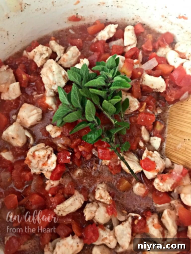 Tomatoes and chicken stock being added to sautéed chicken and vegetables.