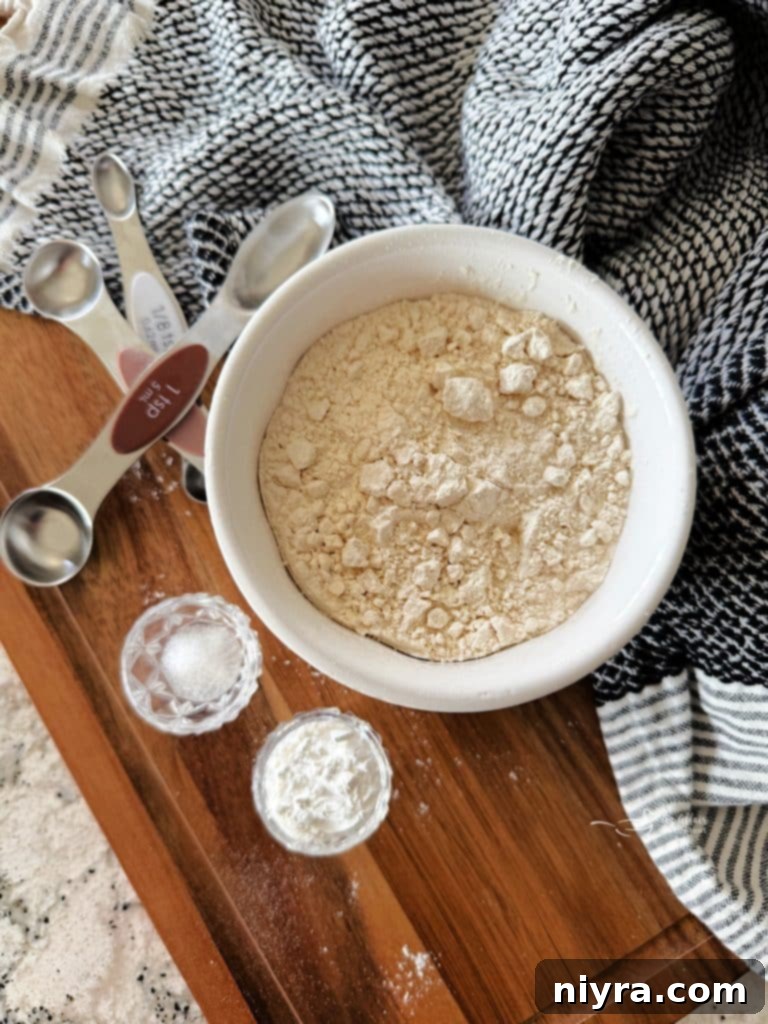 Freshly mixed homemade self-rising flour in a white bowl with a scoop.