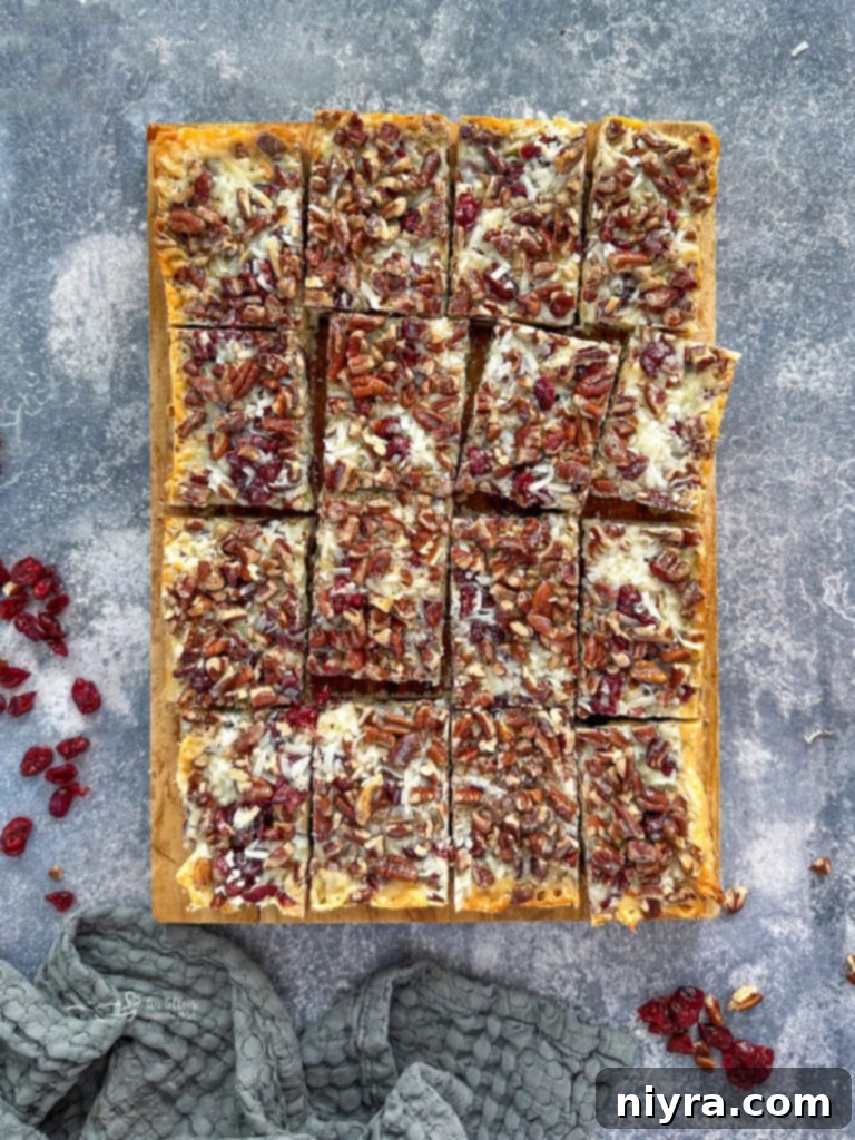 Double Chocolate Cranberry Magic Bars being lifted out of a pan with parchment paper