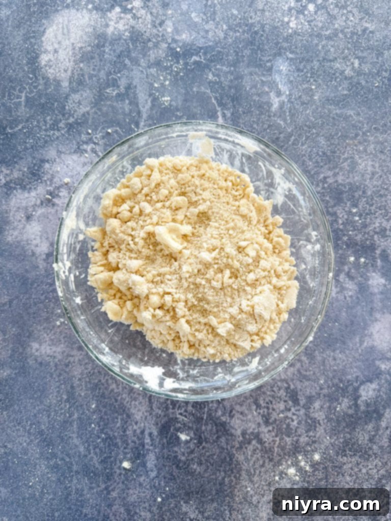 Hands pressing shortbread crust mixture into a parchment-lined baking pan