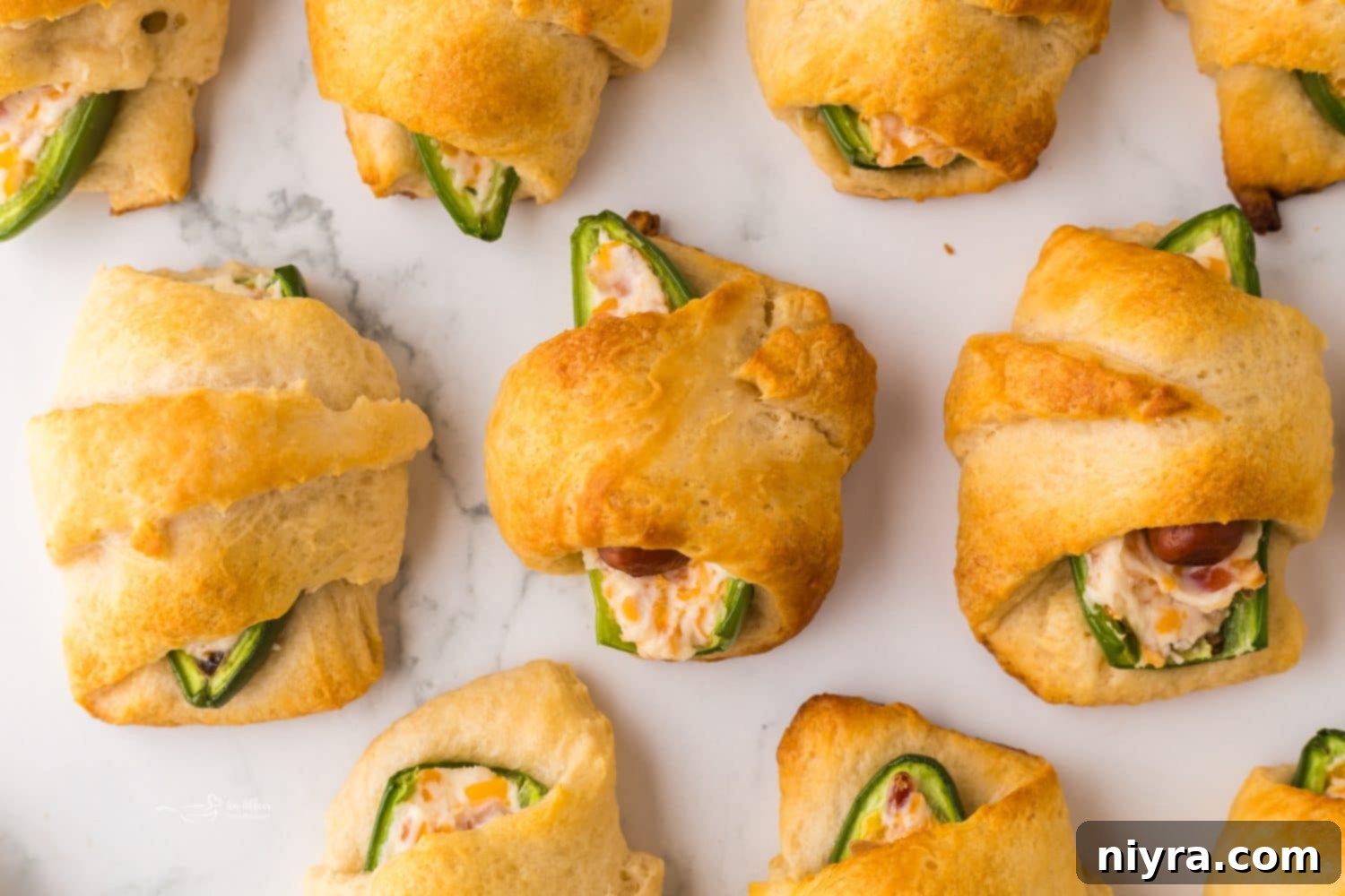 Assembled Jalapeño Popper Pigs in a Blanket arranged on a baking sheet before baking