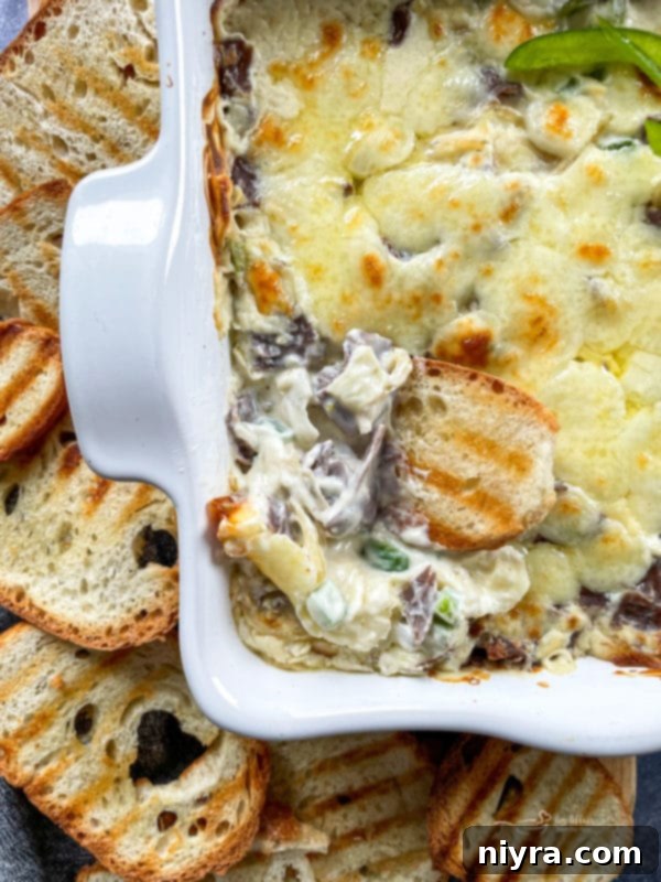 Cheesy Philly Cheese Steak Dip in a white dish, ready to eat