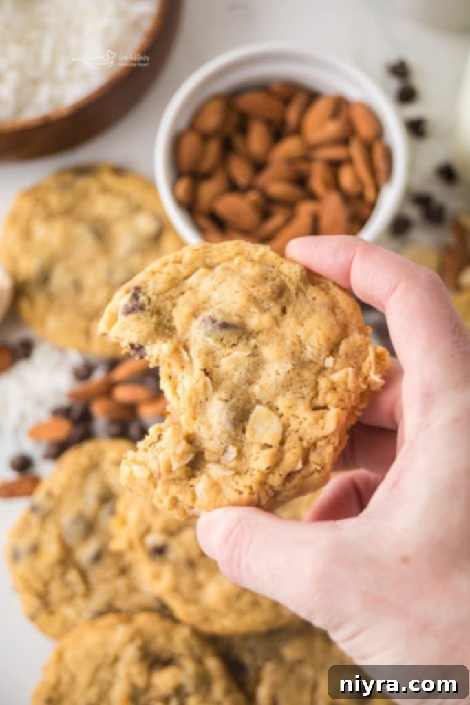 An Almond Joy Cookie on a wooden surface with more cookies in the background