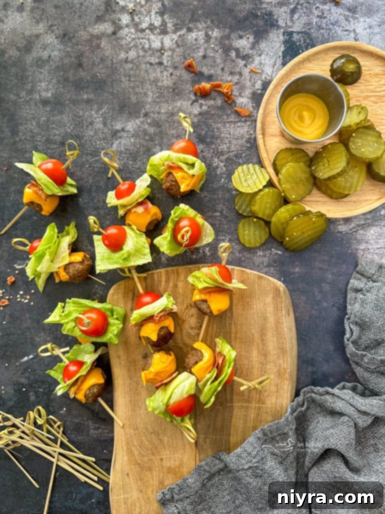 Bacon Cheeseburger Meatballs on a wooden board and a wood plate with pickles on it.