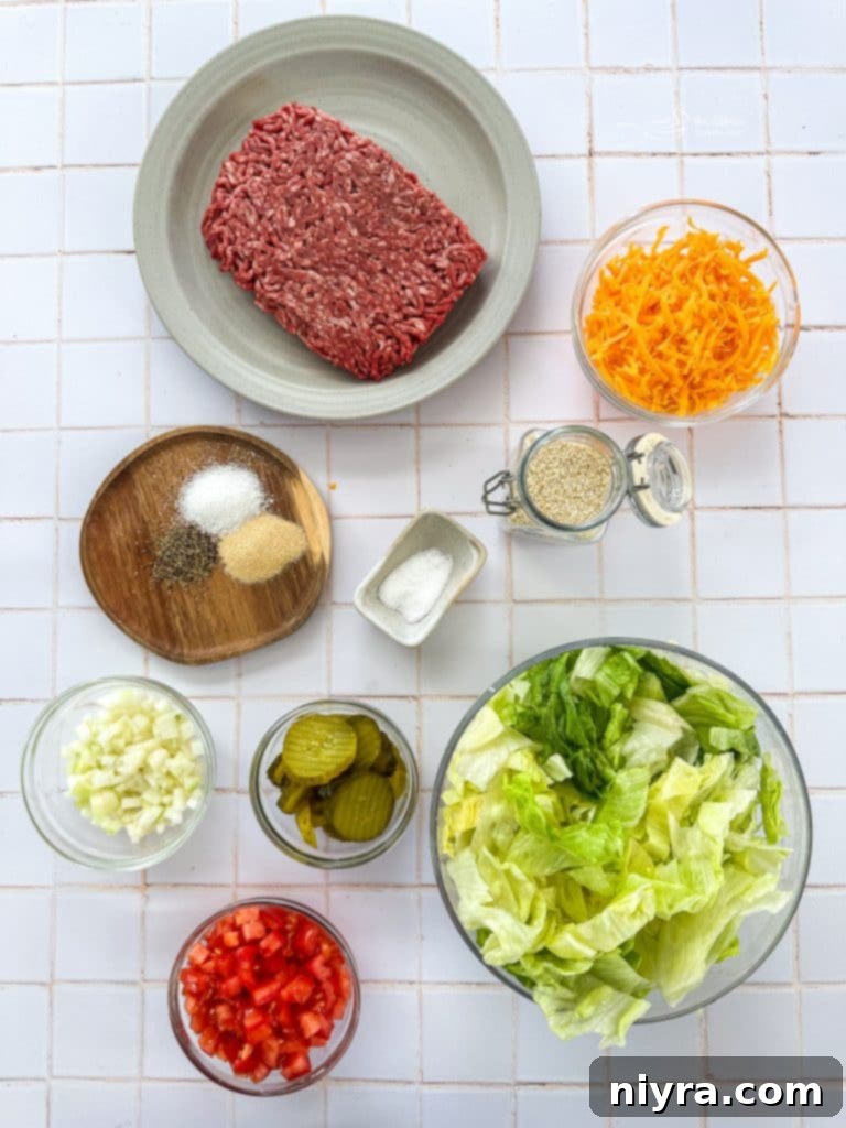Ingredients for Big Mac Salad laid out: ground beef, lettuce, cheese, pickles, onions, tomatoes, and sauce components.