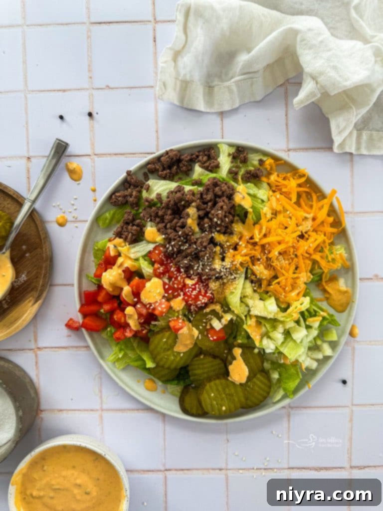 Step-by-step image showing Big Mac Salad ingredients being layered in a large salad bowl.