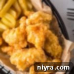 Fiery Honey Crispy Chicken Bites 15 Close up of Hot Honey Popcorn Chicken and french fries in a parchment lined basket.