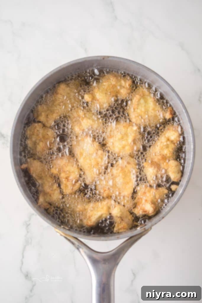 Fiery Honey Crispy Chicken Bites 7 Coating chicken pieces in flour and egg.