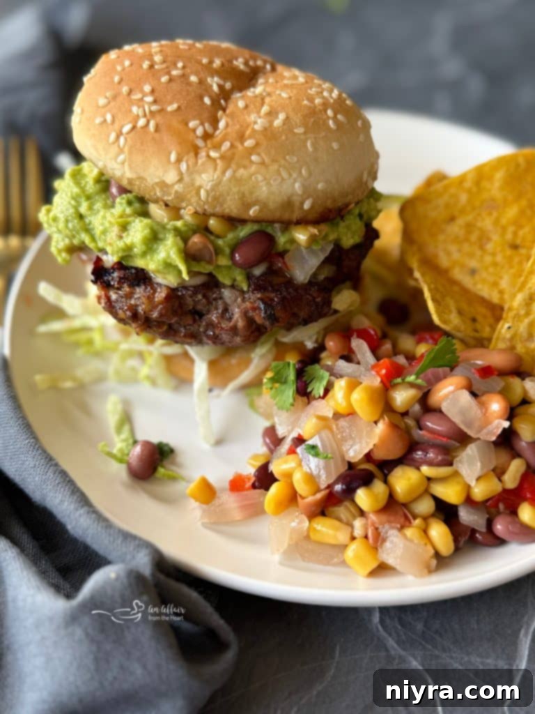 Two Mexican Hamburgers on toasted buns with fresh toppings on a wooden board.