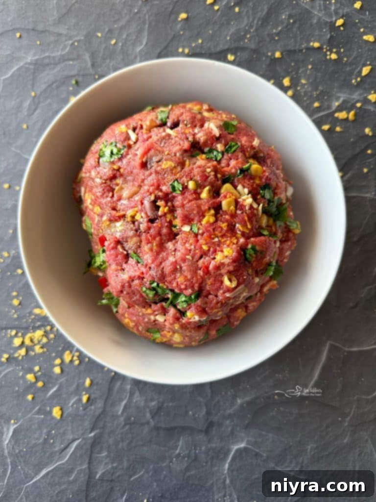 Hand mixing burger ingredients in a bowl.