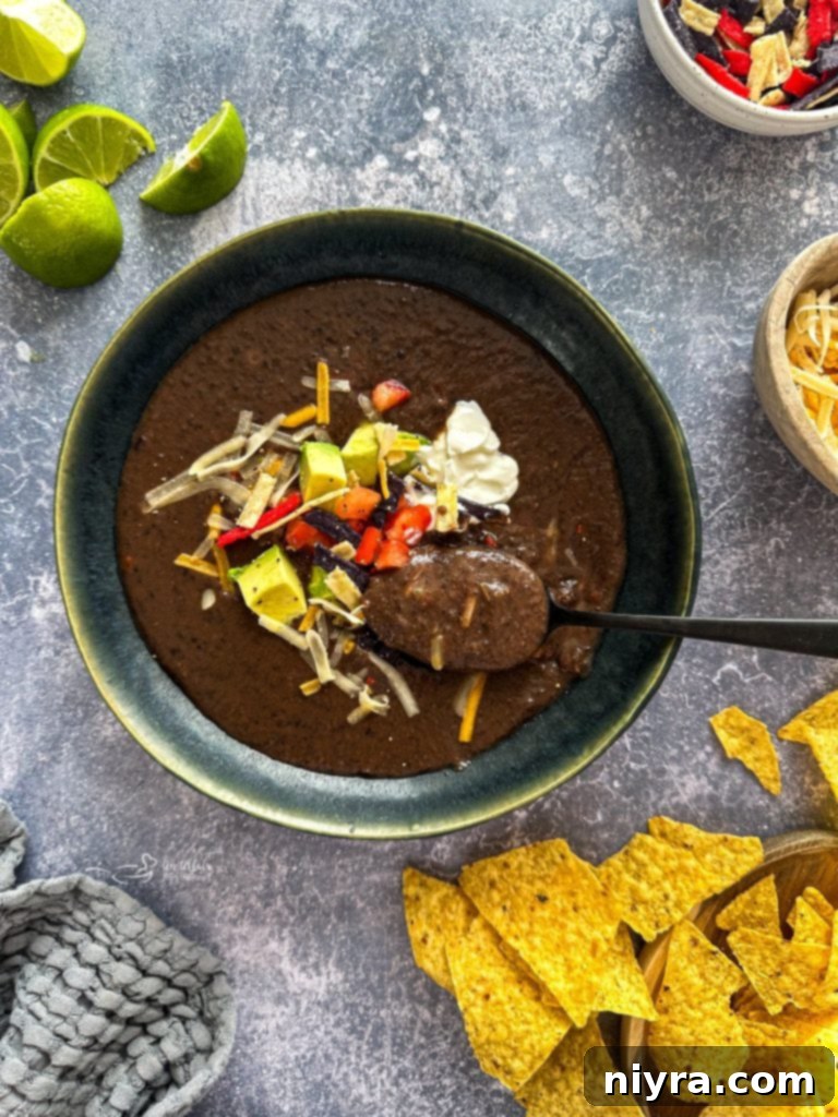 A bowl of creamy black bean soup garnished with fresh cilantro and a dollop of sour cream.