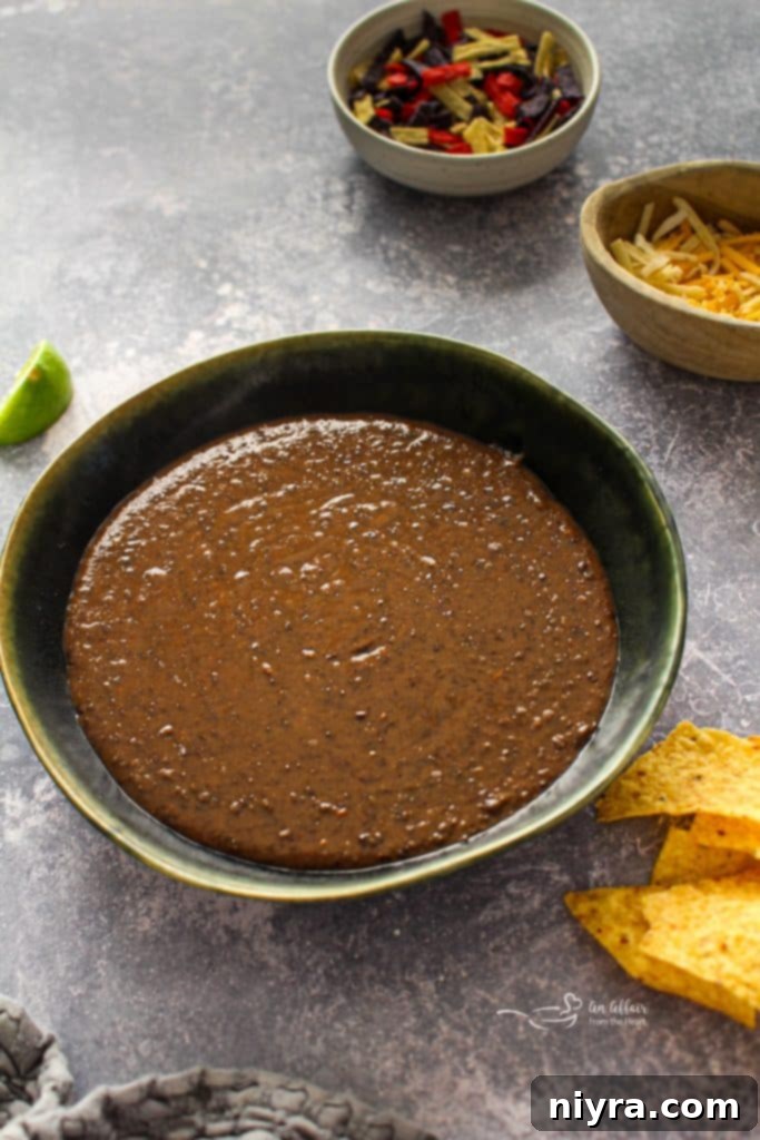 Close-up of black bean soup in a rustic bowl, with a spoon taking a scoop.