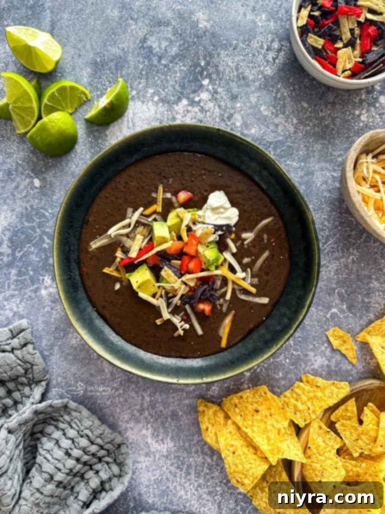 A vibrant bowl of black bean soup topped with various fresh ingredients like avocado and cilantro.