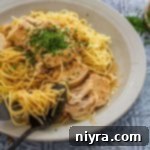 Twisting the pasta with a spoon and fork in a bowl of Slow Cooker Angel Chicken.