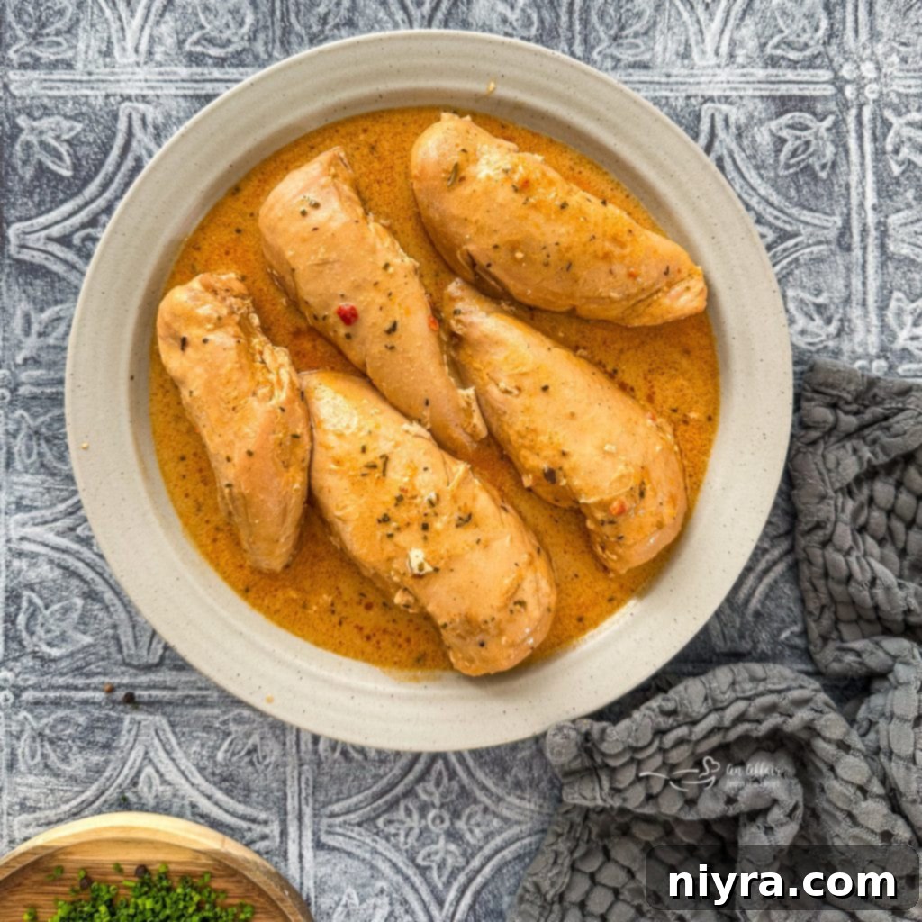 Pouring creamy sauce over chicken breasts in a slow cooker.