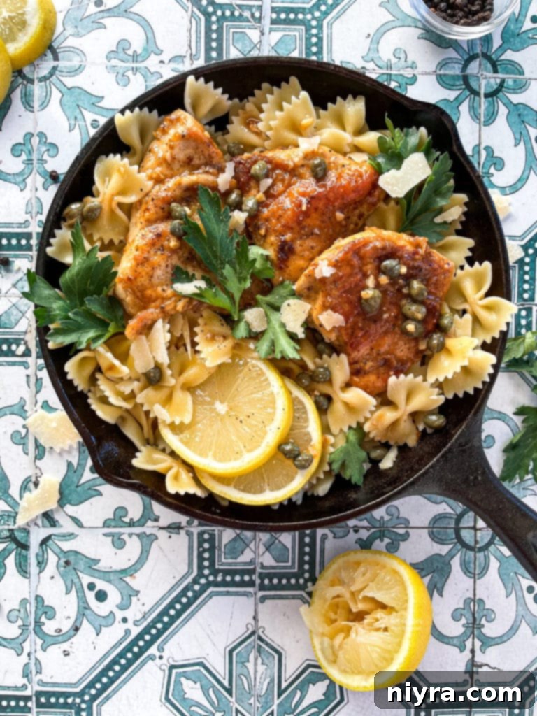 Overhead shot of Chicken Piccata in a pan, garnished with lemon and capers.