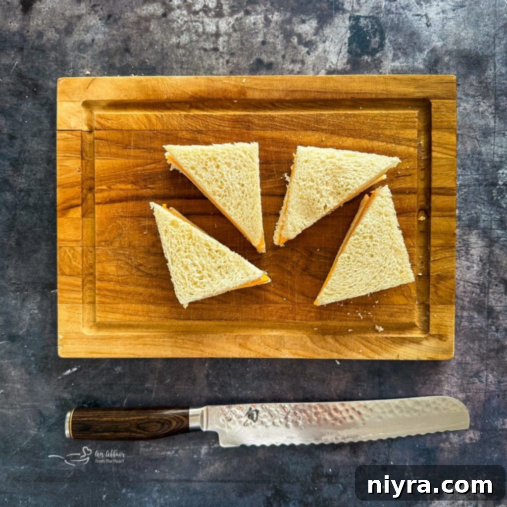 Cutting the crusts off a prepared sandwich to create clean edges.