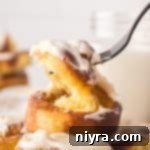 A fork pulling on the Air Fryer Cinnamon Roll, showing the soft fluffy inside.