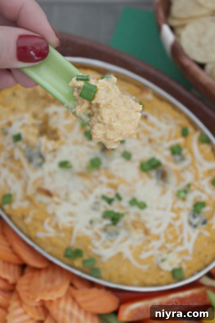 Buffalo Cauliflower Dip ready for dipping, with various fresh vegetables and tortilla chips