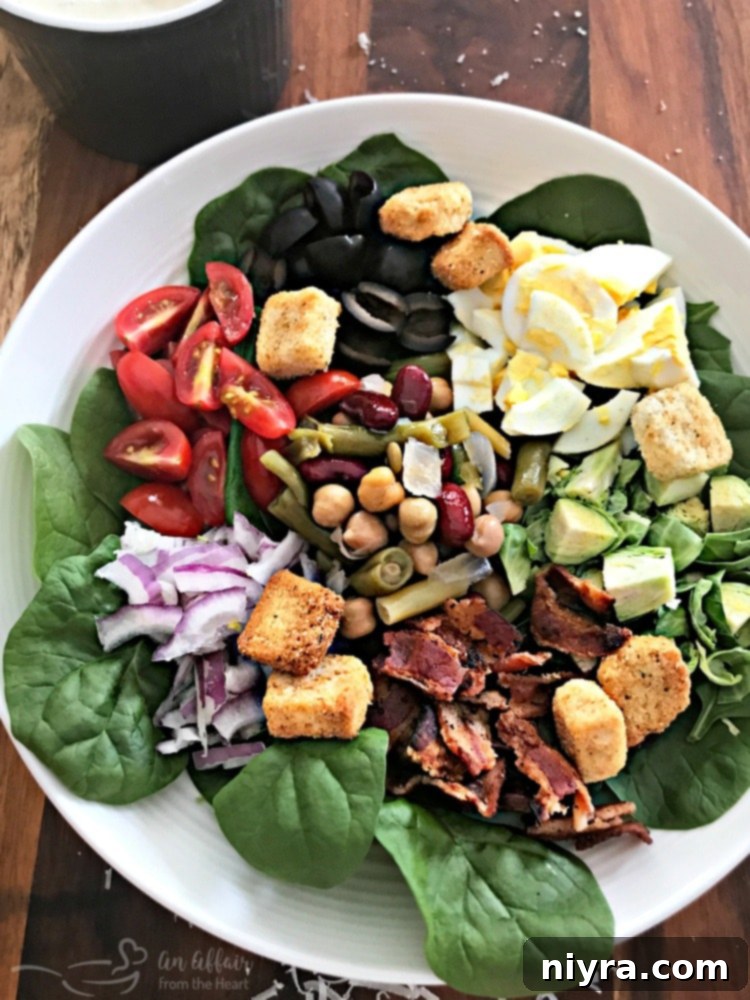 Fully dressed Loaded Spinach Salad with Creamy Roasted Garlic Dressing, ready to be enjoyed.