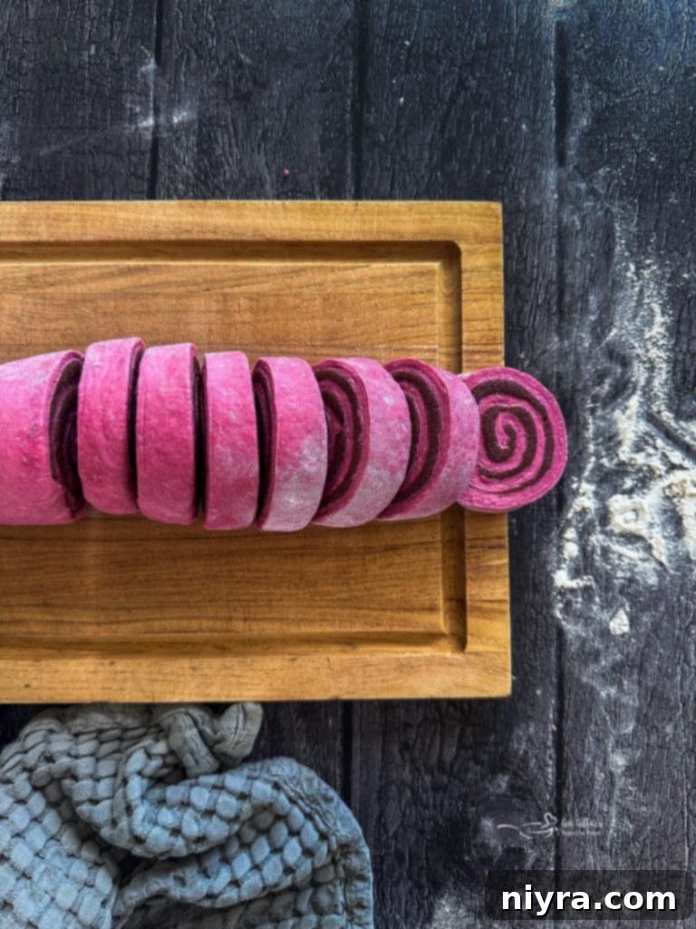 Slicing the Red Velvet Cinnamon Roll log into individual rolls